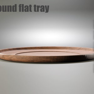 May include: A round wooden tray with a slightly raised edge. The tray is made of dark wood and has a smooth, polished finish.