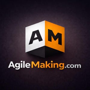 May include: A 3D logo featuring a cube with the letters "AM" in black on white and orange panels. The website address "AgileMaking.com" is displayed below the cube in white and orange text against a dark background.