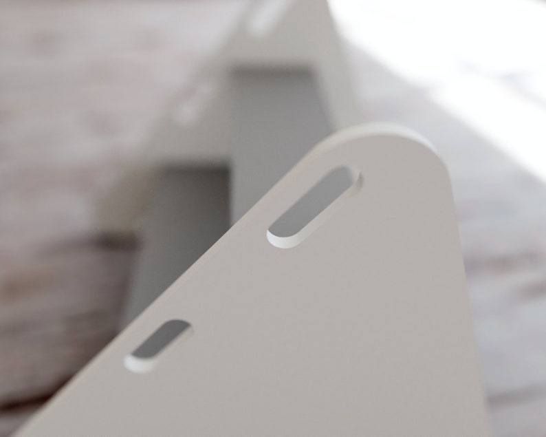 May include: Close-up of two white, triangular wooden storage boxes. Each box has a rounded top with a rectangular cutout. The boxes are positioned at an angle, with one slightly behind the other, creating a sense of depth.