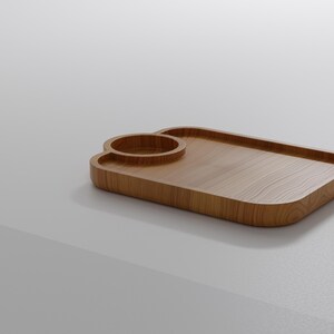 May include: A wooden serving tray with a built-in cup holder. The tray is rectangular with rounded corners and a light brown wood grain finish. The cup holder is a circular indentation. The tray is designed for serving drinks and snacks.