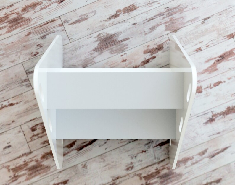May include: A white, two-tiered shelf unit with a distinctive, curved design. The shelf has a rectangular shape with rounded edges and cut-out details on the sides. The unit is made of a solid, opaque white material, suitable for displaying items.