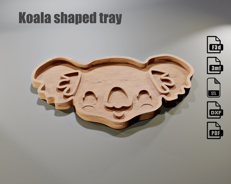 May include: A wooden koala-shaped tray with a smiling face and detailed features. The tray is light brown and has a smooth finish. The text "Koala shaped tray" is at the top. Digital file formats are shown on the right.