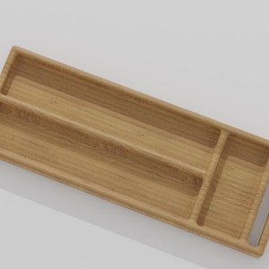 K&ouml;nnte beinhalten: Ein rechteckiges Holztablett mit drei F&auml;chern und einem Griff. Das Tablett besteht aus hellem Holz mit sichtbarer Maserung. Die F&auml;cher sind durch erh&ouml;hte Trennw&auml;nde getrennt, und der Griff ist ein Ausschnitt an der Seite.