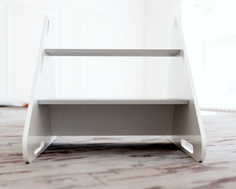 May include: A white wooden step stool with two grey steps. The stool has a simple design with cut-out handles on the sides. The steps are approximately 30 cm wide. The stool is designed for children or for use in the home.