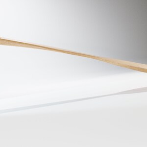 May include: A light-colored wooden spatula with a rectangular blade and a rounded handle. The spatula has a small hole in the handle and is angled slightly upwards. The spatula is likely used for cooking and baking.