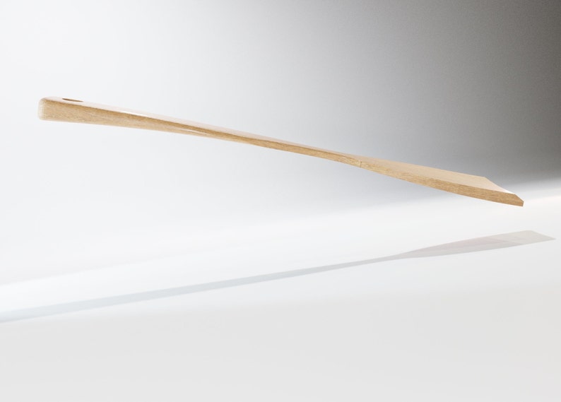 May include: A light-colored wooden spatula with a rectangular blade and a rounded handle. The spatula has a small hole in the handle and is angled slightly upwards. The spatula is likely used for cooking and baking.