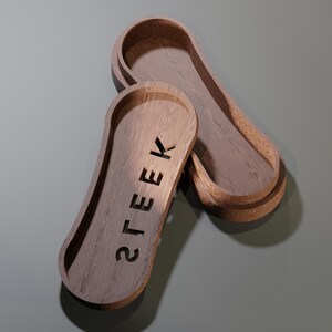 May include: Two wooden trays with a light brown finish. One tray is open, revealing the interior. The word "STEEK" is carved into the surface of the other tray. The trays have a rounded, elongated shape.