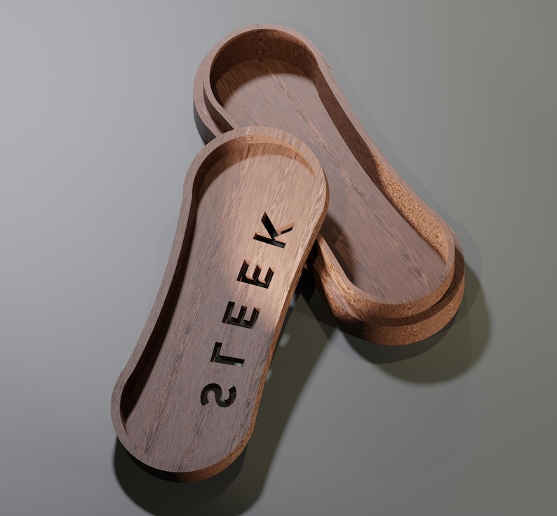 May include: Two wooden trays with a light brown finish. One tray is open, revealing the interior. The word "STEEK" is carved into the surface of the other tray. The trays have a rounded, elongated shape.