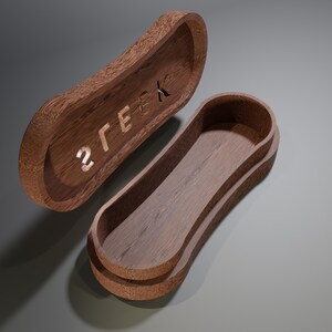 May include: A wooden box with a curved, oblong shape, featuring a lid with the word "2GEEK" carved into it. The box is open, revealing the interior. The wood has a warm, brown tone.
