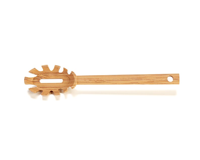 Puede incluir: Un servidor de pasta de madera con un dise&ntilde;o &uacute;nico. El servidor tiene un mango largo y una cabeza plana de forma ovalada con un agujero en el centro. La cabeza est&aacute; dise&ntilde;ada con una serie de peque&ntilde;os dientes puntiagudos alrededor del borde.