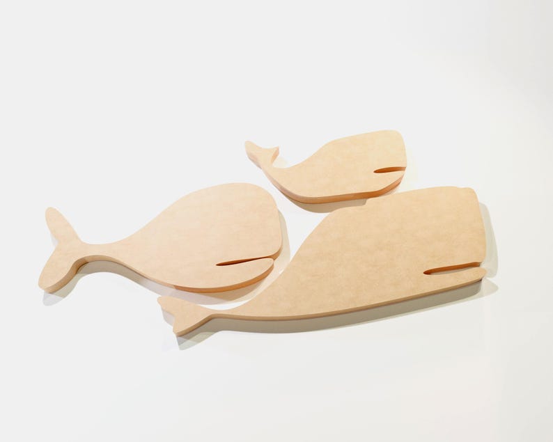 Puede incluir: Tres recortes de ballenas de madera de diferentes tama&ntilde;os. Las ballenas son de color marr&oacute;n claro con un acabado liso y presentan un dise&ntilde;o simple y estilizado. Cada ballena tiene un cuerpo curvo, una cola y una peque&ntilde;a abertura horizontal para la boca.