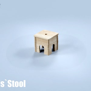May include: A small, light-colored wooden stool with a square seat and arched legs. The stool has a hole in the center of the seat. The text "Kids' Stool" is at the bottom of the image, with "CNC" at the top left.