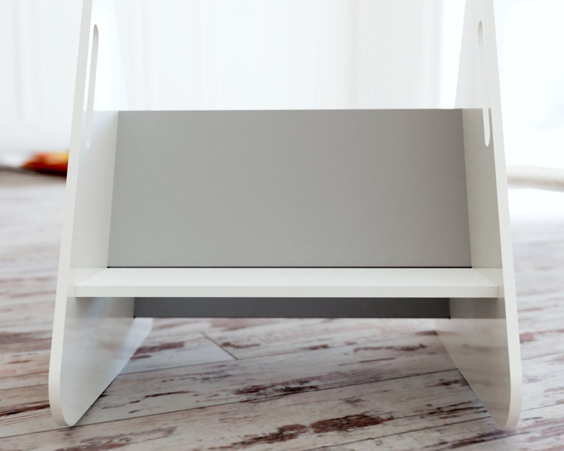 May include: A white wooden step stool with a gray interior and a single shelf. The stool has cut-out handles on the sides and is designed for children or to reach higher places. The stool is on a wooden floor.