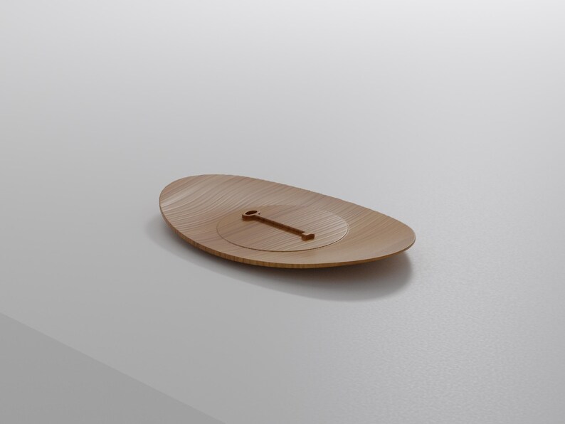 May include: A wooden, oval-shaped tray with a carved, circular indentation and a small, rectangular handle. The tray has a light brown color and a smooth, polished finish. The design is minimalist and modern.
