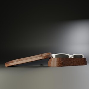 May include: Sunglasses with a white frame and dark lenses rest inside a wooden case. The case is open, with the lid slightly ajar. The case and lid are made of a dark wood.