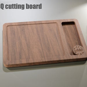 Puede incluir: Tabla de cortar de barbacoa rectangular de madera con un &aacute;rea empotrada y un compartimento m&aacute;s peque&ntilde;o. La tabla tiene un patr&oacute;n de vetas de madera natural y el texto "BBQ cutting board" est&aacute; en la parte superior. Un logotipo circular es visible.