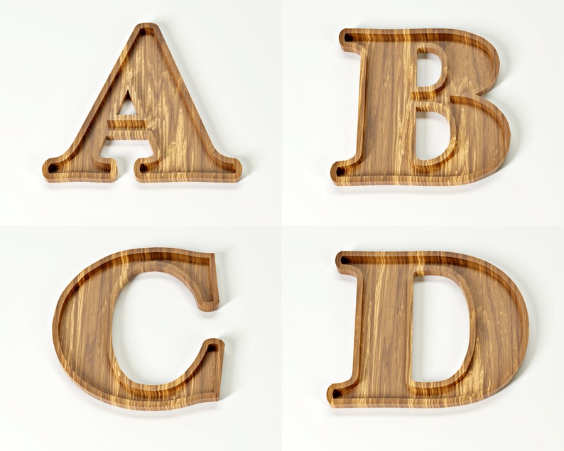 May include: Four wooden letter trays: A, B, C, and D. Each letter is carved from light brown wood with a visible grain pattern. The trays have a shallow, recessed design, perfect for holding small items. The letters are displayed against a white background.