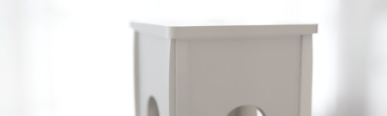 May include: A close-up of a white, rectangular, wooden structure with rounded holes. The structure has a flat top and is painted in a solid, neutral white color. The background is blurred, suggesting a bright, natural light source.