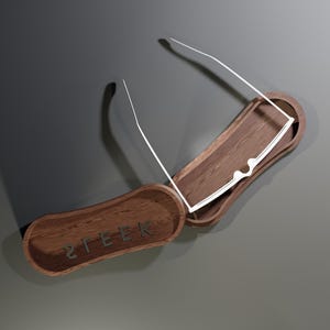 May include: A wooden eyeglasses case with a pair of white-framed glasses inside. The case is open, revealing a dark interior. The word "STEEK" is engraved on the lid. The case is made of dark wood.