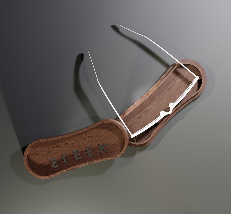 May include: A wooden eyeglasses case with a pair of white-framed glasses inside. The case is open, revealing a dark interior. The word "STEEK" is engraved on the lid. The case is made of dark wood.
