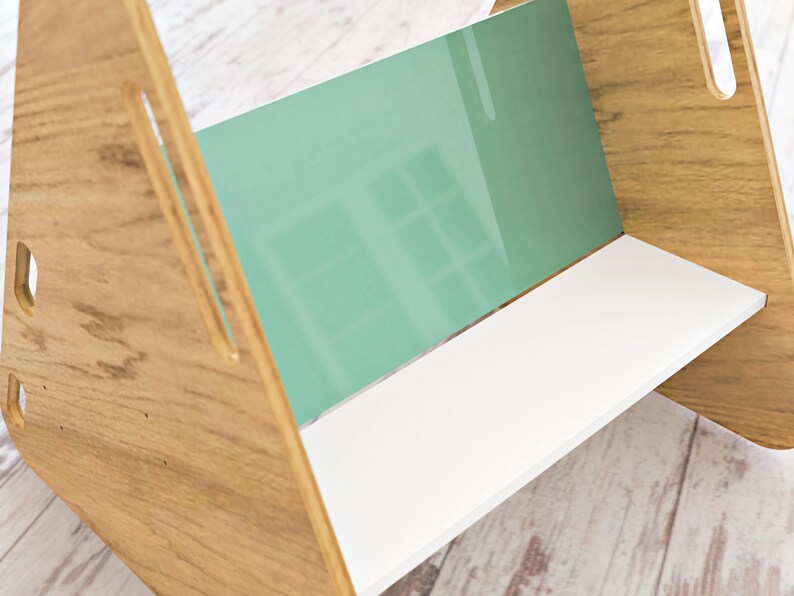 May include: A wooden bookshelf with a light brown finish, featuring a white shelf and a mint green back panel. The design includes cut-out handles on the sides, creating a modern and minimalist aesthetic.