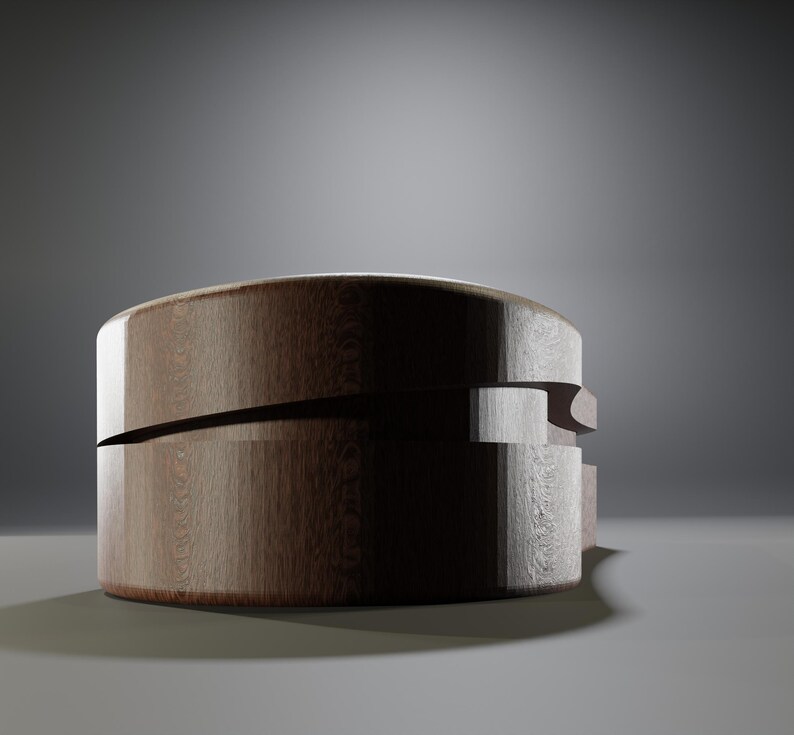 May include: A round, wooden box with a dark brown finish. The box has a unique design with a horizontal cut across the middle and a layered side detail. The wood grain is visible, adding texture. The box sits on a light gray surface.