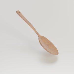 May include: A light-colored wooden spoon with a long handle and a wide, oval-shaped head. The spoon has a small hole at the end of the handle for hanging. The wood grain is visible, giving it a natural appearance. The spoon is angled slightly.