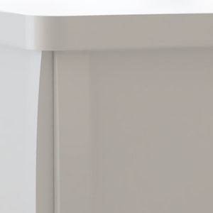 May include: Close-up of a section of a white cabinet or furniture piece. The image highlights the corner, showing the edge and a recessed panel. The finish appears smooth and matte, with a clean, modern aesthetic.