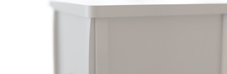 May include: Close-up of a section of a white cabinet or furniture piece. The image highlights the corner, showing the edge and a recessed panel. The finish appears smooth and matte, with a clean, modern aesthetic.