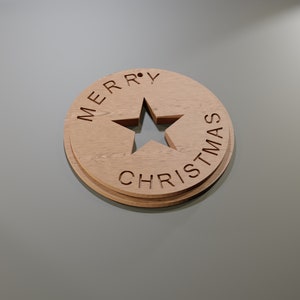 May include: Wooden Christmas ornament with a star cutout in the center. The words "MERRY CHRISTMAS" are carved around the star. The ornament is made of light brown wood and has a layered design.