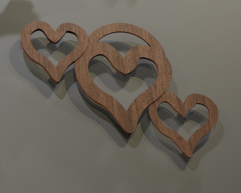 May include: Three wooden heart-shaped wall decorations. The hearts are cut from a light brown wood and are arranged in a cluster. The wall behind the hearts is a solid gray color. The hearts are casting shadows.