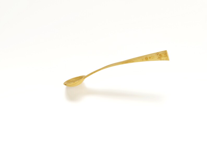 May include: A gold-colored metal spoon with a rounded bowl and a long, slender handle.