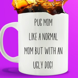 May include: White ceramic coffee mug with black text that reads "Pug Mom Like a Normal Mom But With an Ugly Dog!" The mug is filled with coffee and has a splash of coffee on the top.