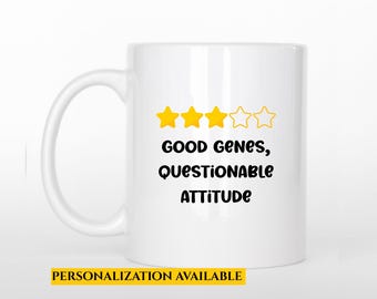 May include: A white ceramic mug with a black handle. The mug features the text "GOOD GENES, QUESTIONABLE ATTITUDE" with three yellow star icons. The words "PERSONALIZATION AVAILABLE" are in a yellow rectangle at the bottom.