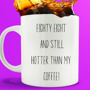 May include: White ceramic coffee mug with black text that reads "Eighty Eight and Still Hotter Than My Coffee!"