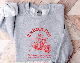 May include: Gray sweatshirt with a red graphic of a person riding a motorcycle. The text reads "It's Been Fun But imma go have an existential crisis now."