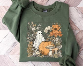 Op de afbeelding: Groen sweatshirt met een Halloween-thema. Het ontwerp toont een witte geest, een oranje pompoen, paddenstoelen en bloemen in oranje, wit en beige. Het sweatshirt heeft lange mouwen en een ronde hals.
