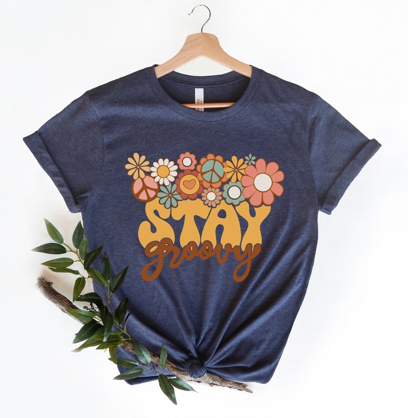 May include: A navy blue t-shirt with a yellow "Stay Groovy" graphic and a floral design in shades of pink, orange, green, and blue.