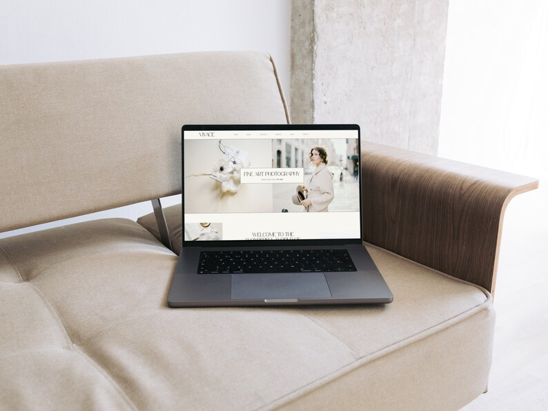 K&ouml;nnte beinhalten: Ein Laptop-Computer, auf dem eine Website f&uuml;r Fine-Art-Fotografie angezeigt wird. Die Website zeigt eine wei&szlig;e Blumenarrangements und eine Frau in einem wei&szlig;en Mantel und einem Hut.