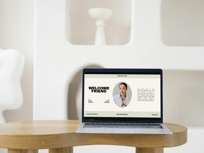 May include: A laptop displaying a website with the text "WELCOME FRIEND" in bold black letters. The website features a photo of a person and additional text. The laptop sits on a round wooden table.