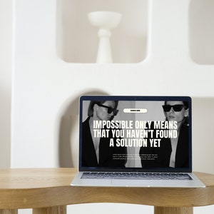 Puede incluir: Un ordenador port&aacute;til con un fondo blanco. La pantalla muestra un sitio web con el texto "Imposible solo significa que a&uacute;n no has encontrado una soluci&oacute;n".