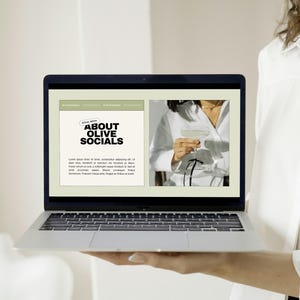 May include: A laptop displaying a website with the text "ABOUT OLIVE SOCIALS." The website features a photo of a person holding a cocktail. The laptop is held by a person wearing a white shirt.