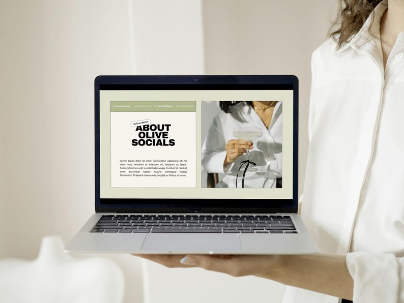 May include: A laptop displaying a website with the text "ABOUT OLIVE SOCIALS." The website features a photo of a person holding a cocktail. The laptop is held by a person wearing a white shirt.