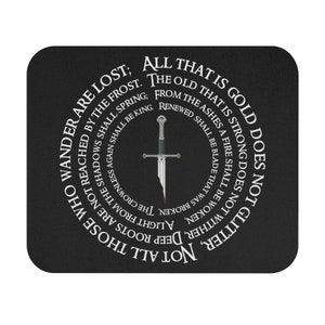 May include: A black mouse pad with a white circle containing a silver sword and the text "Not all those who wander are lost; All that is gold does not glitter, Not all those who wander are lost; The old that is strong does not wither, Deep roots are not reached by the frost, From the ashes a fire shall be woken, A light from the shadows shall be kindled, The crownless again shall be king, Renewed shall be blade that was broken,  Spring;"