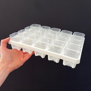 May include: White plastic tray with 20 individual square-shaped compartments. The tray is designed for starting seeds or propagating plants.