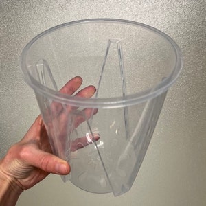 May include: Clear plastic plant pot with drainage holes and a ribbed design. The pot is designed to be stackable.