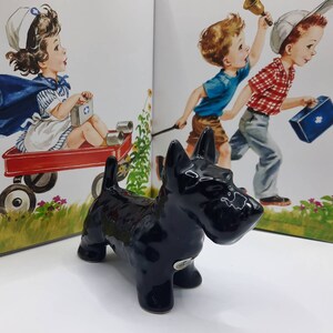May include: Black ceramic Scottish Terrier figurine. The figurine is standing on a white surface.