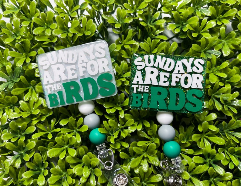 Pu&ograve; includere: Due portabadge con glitter verde e bianco con il testo "Sundays Are For The Birds" su ciascuno. I portabadge hanno perline bianche, grigie e verdi.