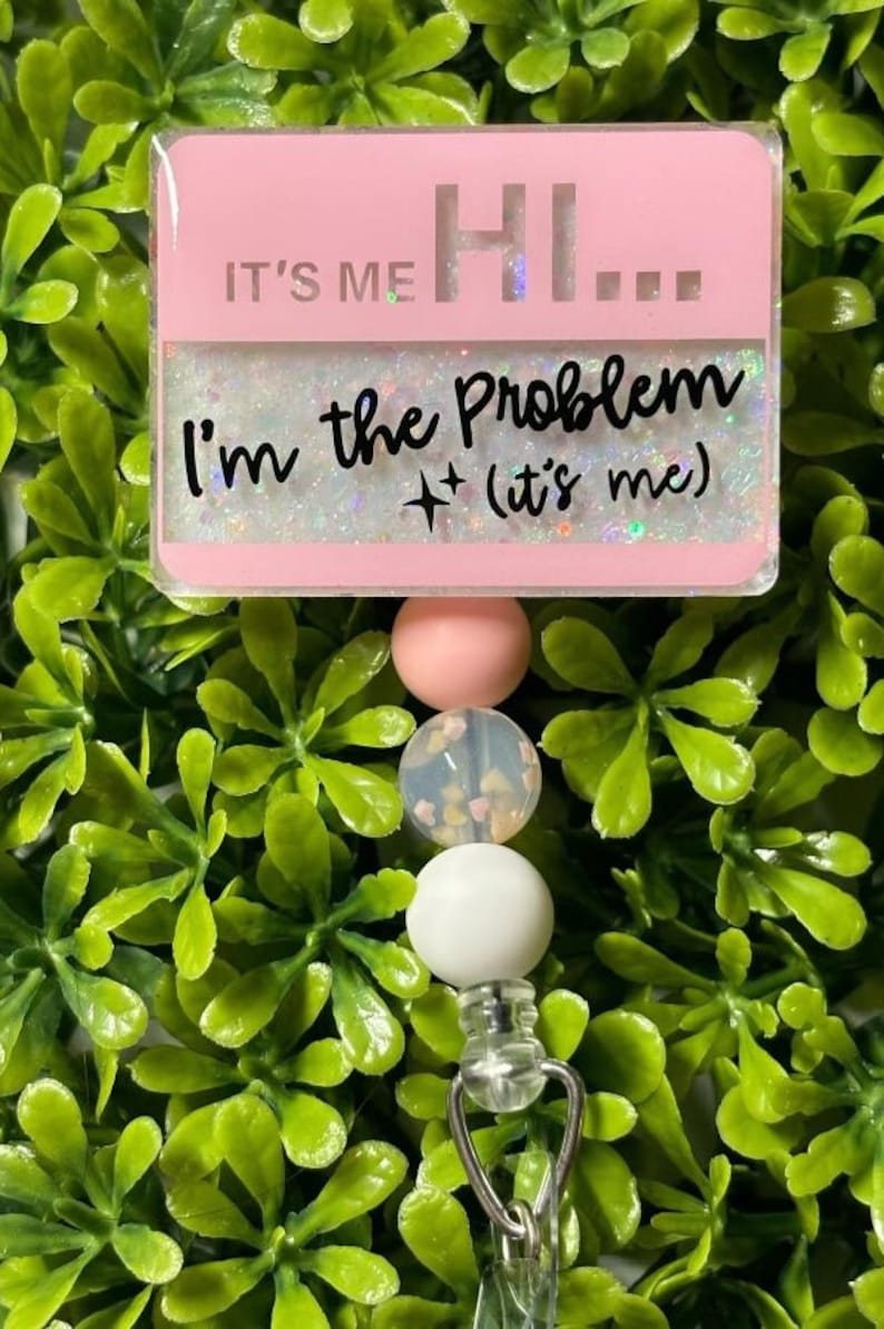 May include: Pink and white beaded retractable badge holder with a pink rectangle charm that says "It's Me Hi... I'm the Problem + (it's me)"