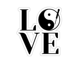 May include: A black and white sticker featuring the word "LOVE" in a bold, sans-serif font. The letter "O" is replaced by a yin-yang symbol with an acupuncture needle. The sticker has a white border, set against a white background.